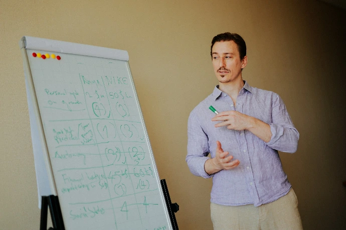 Man standing near a whiteboard with notes.